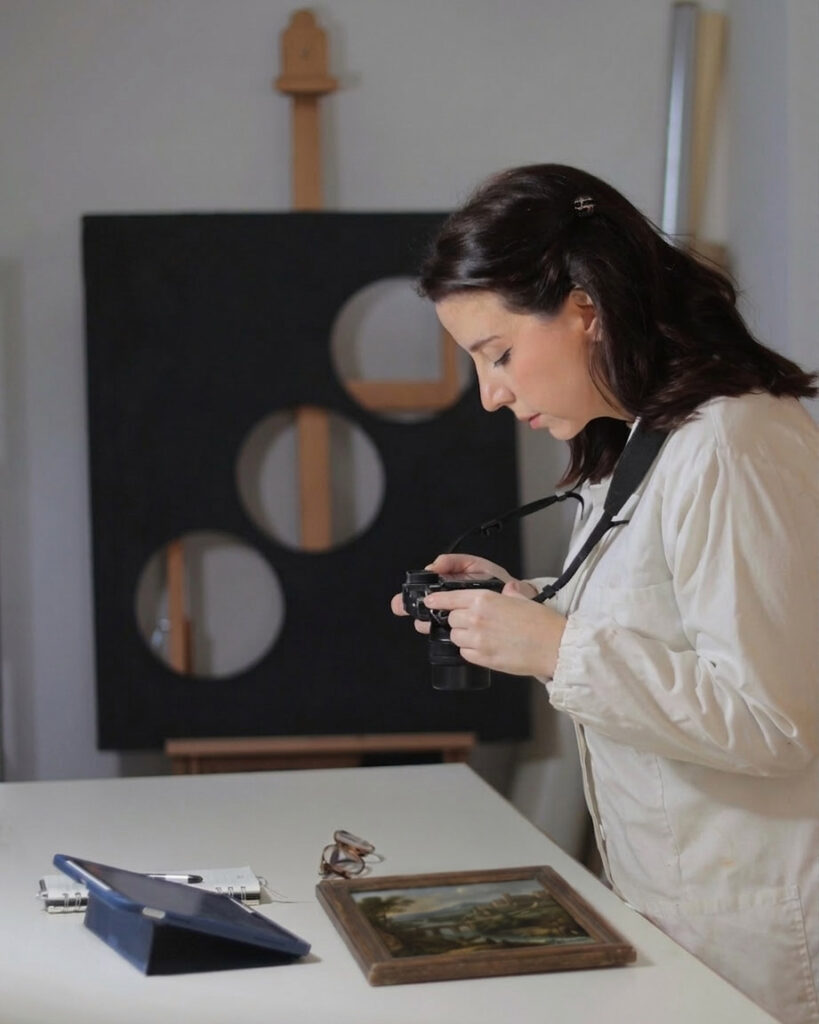 Esame ravvicinato di un quadro antico per valutarne lo stato di conservazione, laboratorio di restauro a Darfo Boario Terme